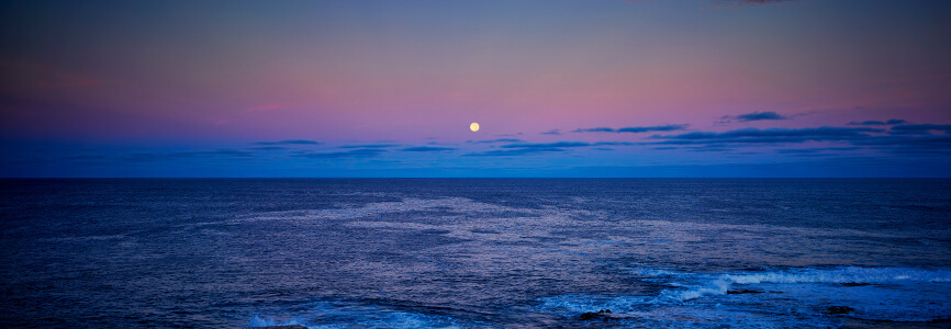 moon rising over the ocean at dusk